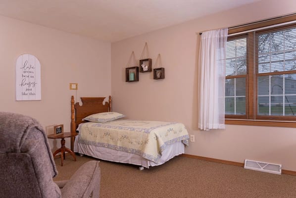 A cozy bedroom featuring a bed, side table, and decorative wall shelves.
