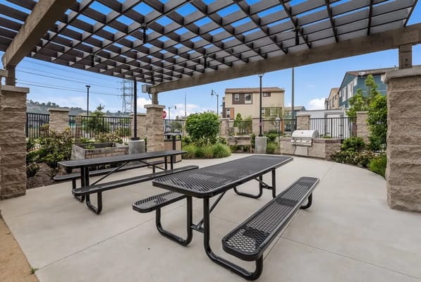 Outdoor patio area with benches and a grill