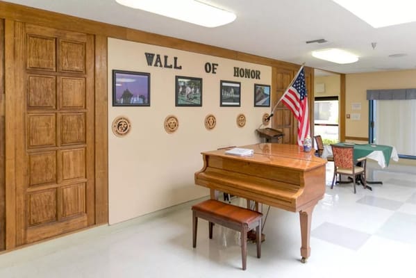 Interior view of a common area with a piano and a wall of honor