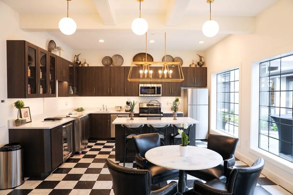 A modern kitchen with a marble island and black and white checkered flooring.