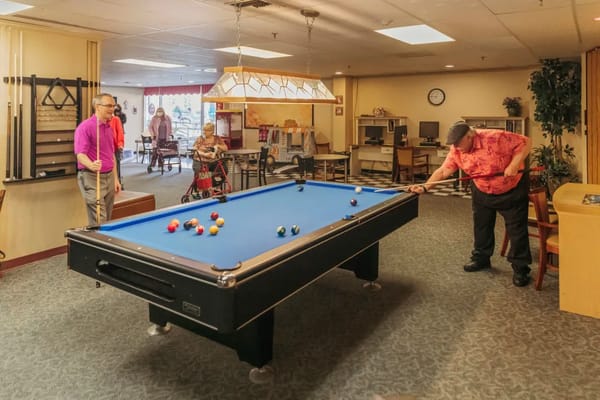 Two residents playing billiards in the game room