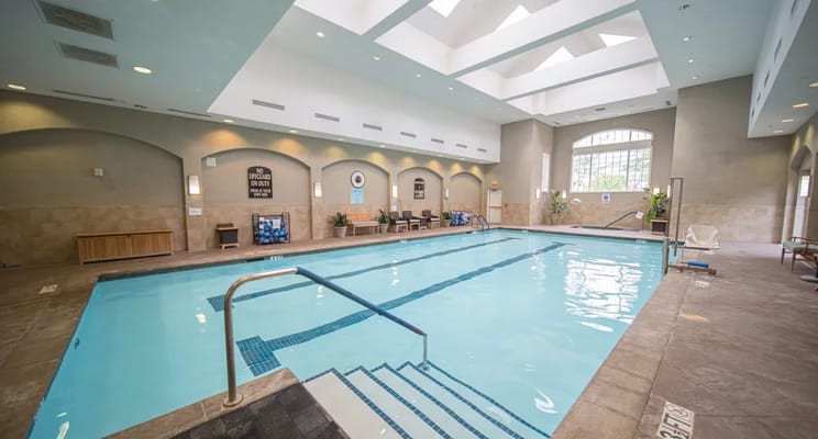 Indoor swimming pool with natural light and seating area