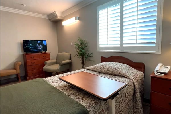 A cozy resident room featuring a bed, TV, and seating area.