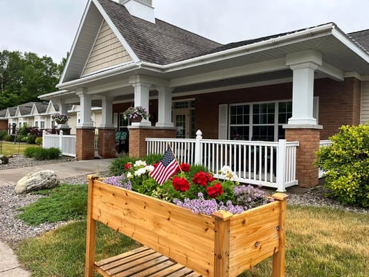 Flower planter with red and purple flowers in front of Cedar Cove Assisted Living.