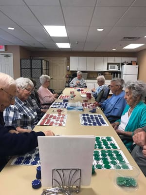 Seniors participating in a bingo game at a community table.