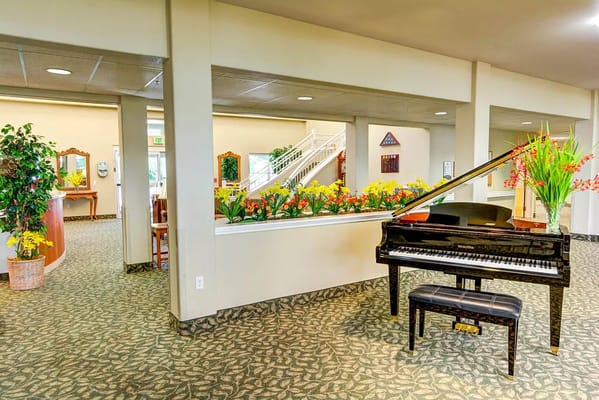 Interior view of a common area with a piano and flowers