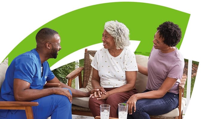Nurse engaging with a resident and family member outdoors