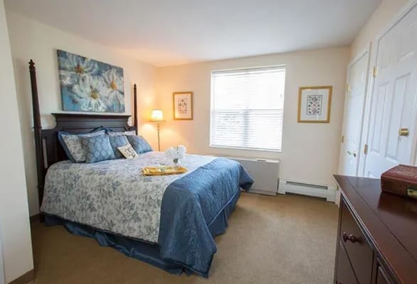 Well-decorated bedroom featuring a bed with blue bedding and natural light from a window.