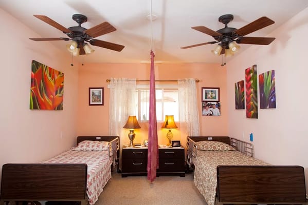 A shared bedroom with two beds, decorative paintings, and a lamp.