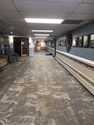 Interior hallway with artwork and seating at Cherrelyn Healthcare Center.
