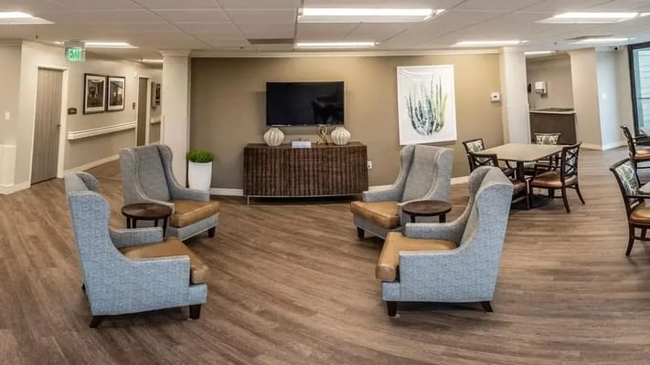 A cozy lounge area with grey chairs and a television.