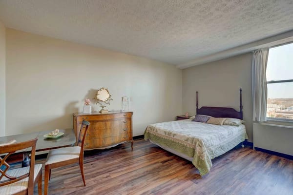 Neatly arranged bedroom with a bed and wooden furniture