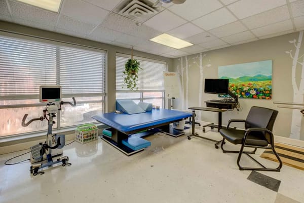 A therapy room with exercise equipment and a treatment table.