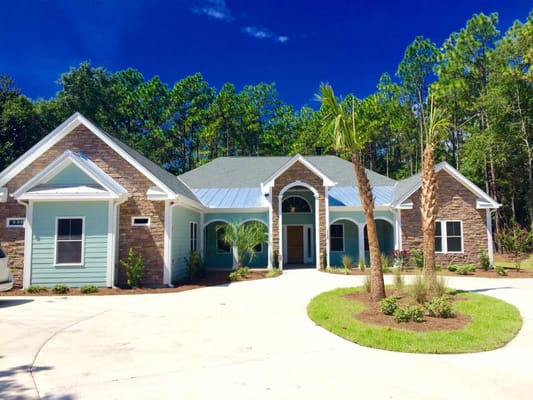 Front view of Coastal Cove of Wilmington senior living facility surrounded by greenery