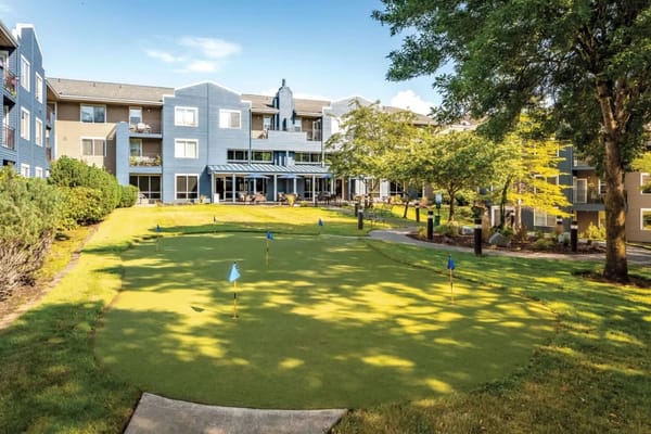 Bright outdoor space with a putting green and building facade