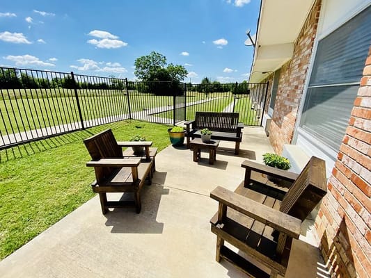 Outdoor patio with wooden chairs and a small table at Colonial Manor Nursing Center