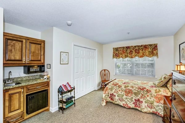 Cozy private resident room with a kitchenette and floral bedding