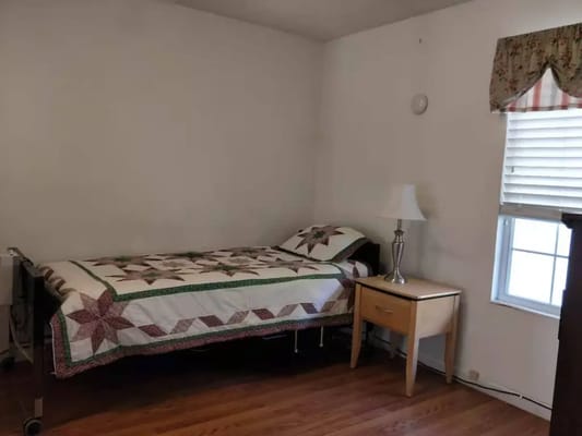 Cozy resident room with a quilted bedspread and lamp