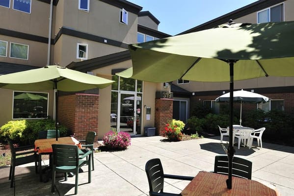 Outdoor seating area with green umbrellas and tables at Conservatory Place.