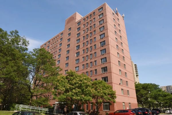 A tall red brick building surrounded by trees