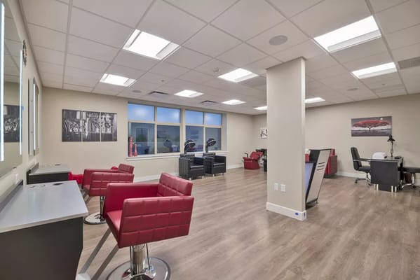 Interior of the salon area featuring red chairs and styling stations.