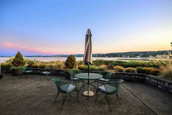 Outdoor patio area with green chairs and table facing a scenic view