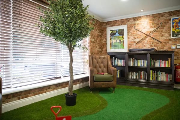 A tranquil lounge space with a chair, bookshelf, and artificial tree.