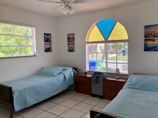 Bright bedroom with two beds and a colorful window