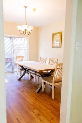 Dining area with a wooden table and chairs, large window, and light fixture