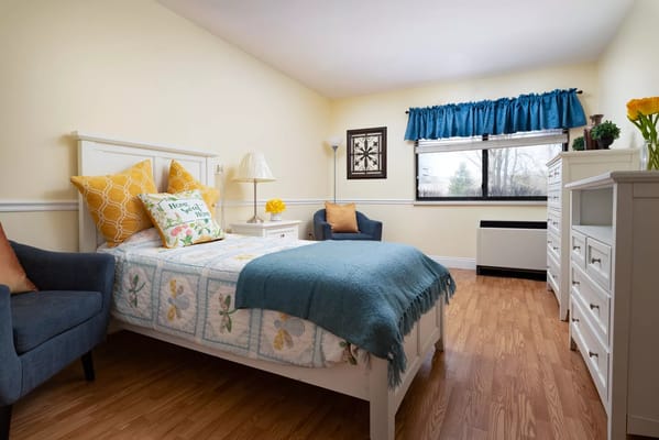 Cozy bedroom with a bed, blue blanket, and seating area