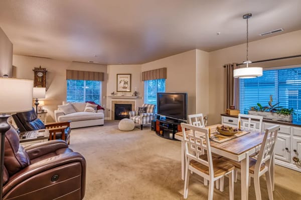A spacious living room with a fireplace, plush seating, and dining area.