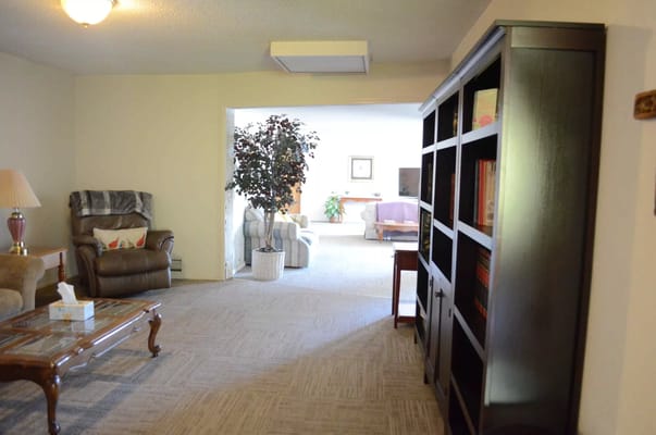 Living area featuring a comfortable chair, bookshelf, and plants
