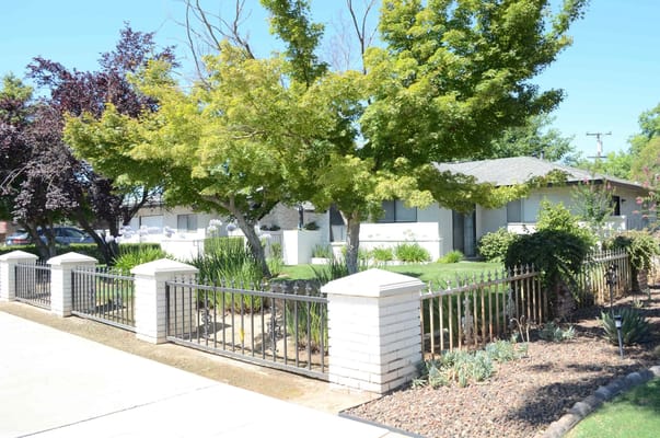 Front view of Evergreen Life Care Homes with landscaped gardens and iron fence.