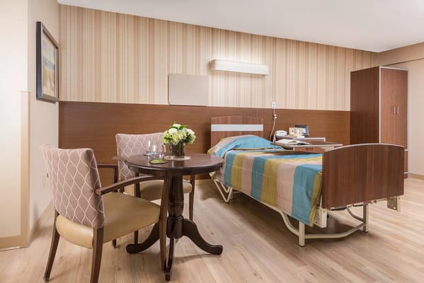 Bright private resident room with a bed and table