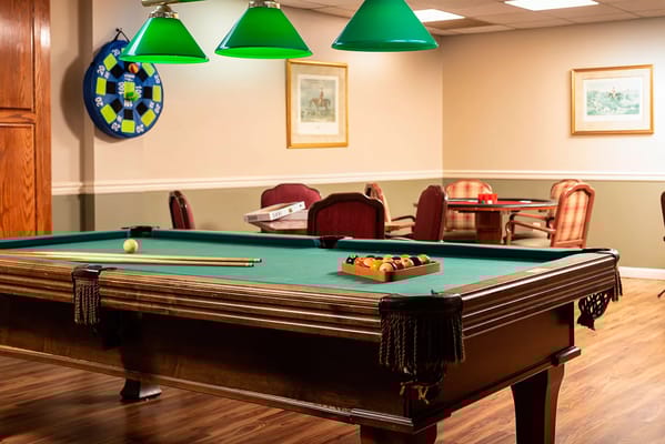 Billiards table with pool balls and cues in a game room