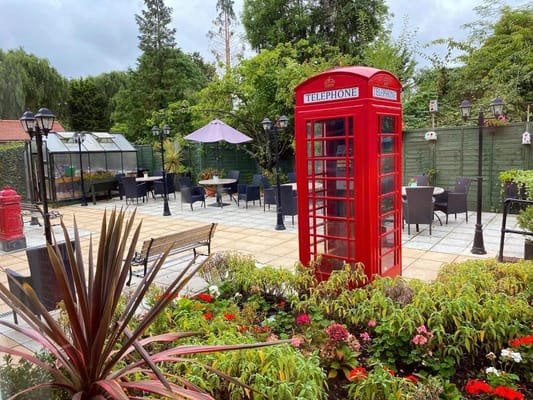 A vibrant outdoor patio area with flowers and a telephone booth