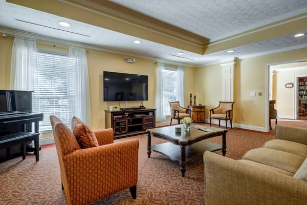 Spacious living room with orange chairs, a coffee table, and a television.