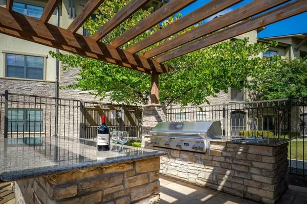 Outdoor grill area with stone counter and wine bottle