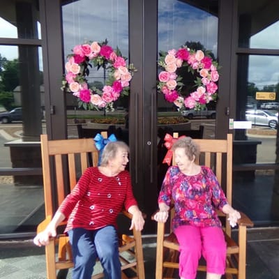 Two residents enjoying rocking chairs at the entrance.