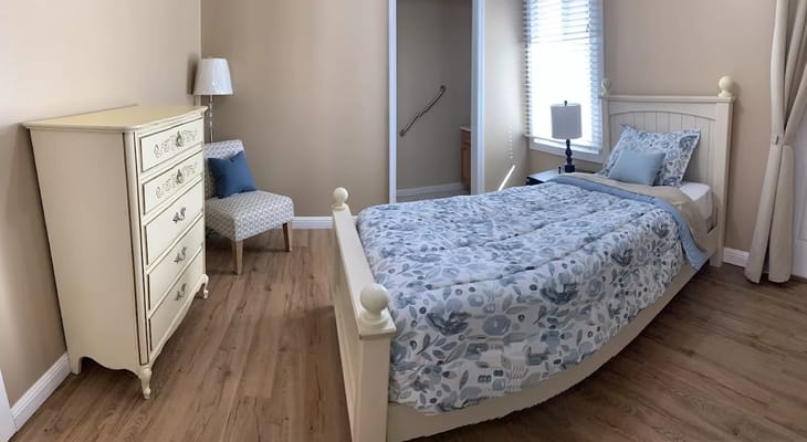 A well-furnished bedroom with a bed, dresser, and chair.