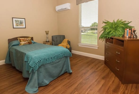 A well-decorated private bedroom featuring a bed, chair, and natural light.