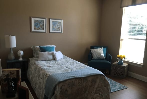 A cozy bedroom featuring a bed, armchair, and decorative items.