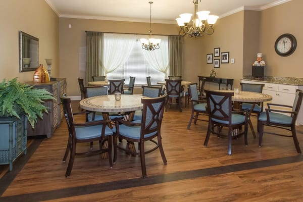 A spacious dining room with round tables and comfortable chairs.