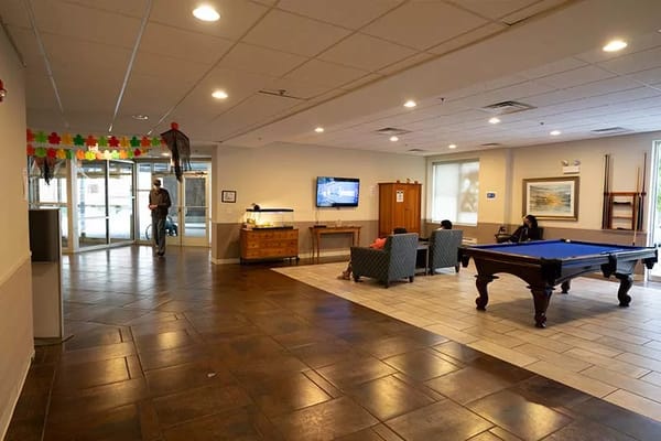 Residents socializing in a common area with a pool table