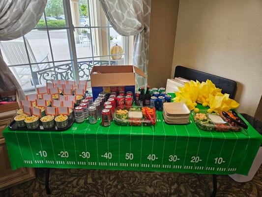 A table with a football-themed tablecloth displaying snacks and drinks.