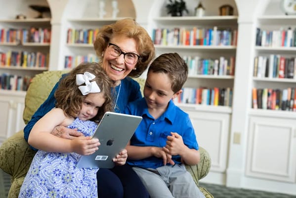 A joyful senior resident interacting with two children indoors