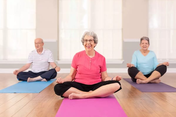 Seniors practicing yoga in a bright activity room