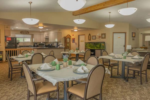 Bright dining room with neatly set tables and a kitchen area