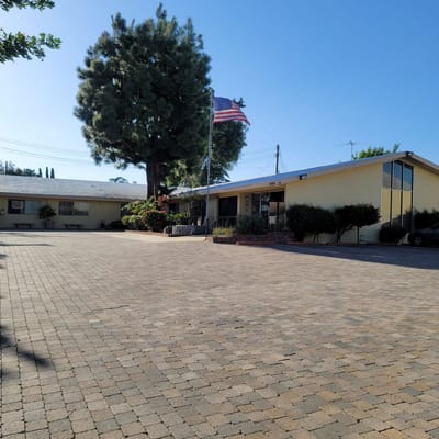 The front entrance of El Monte Convalescent Hospital with an American flag and landscaped area.