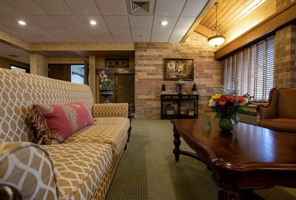 Cozy common area with a patterned sofa, wooden coffee table, and flower arrangement